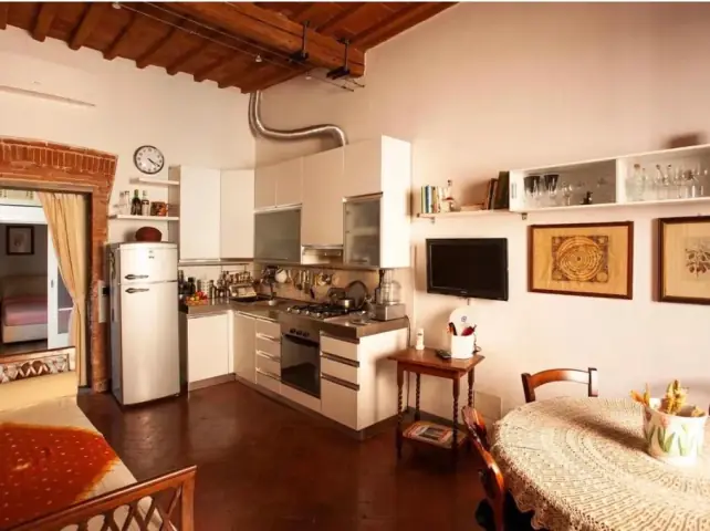 Soggiorno con cucina a vista e soffitto a travi